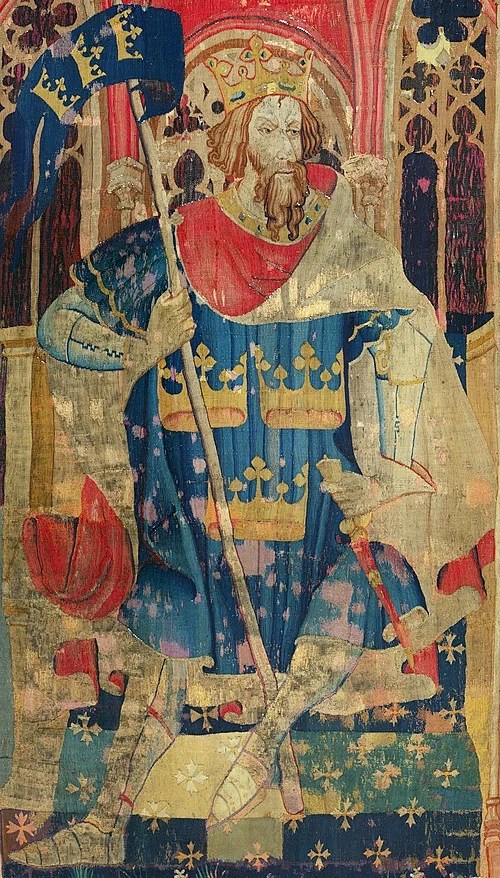 A regal figure in medieval attire, seated on a throne, holding a flag and a staff. The figure wears a crown and a decorated robe, surrounded by ornate architectural elements.